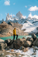 Tourist man at Mount Fitzroy, Patagonia trek. Scenic view of snowcapped mountain tops. Blue sky, turquoise blue lake and scenic rock landscape. Shot in Argentina. Nature, travel, adventure, hiking.