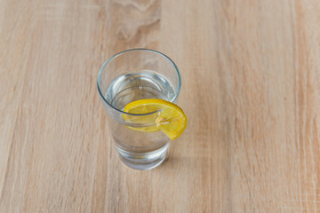 Glass with water and lemon on wooden table