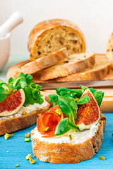Toast from swiss twisted bread, with feta cheese or ricotta, fresh figs, rolled slice of bacon, fresh leaves of corn or valerian salad and crushed pistachio nuts. With touch of lime juice.