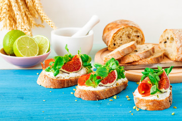 Toast from swiss twisted bread, with feta cheese or ricotta, fresh figs, rolled slice of bacon, fresh leaves of corn or valerian salad and crushed pistachio nuts. With touch of lime juice.