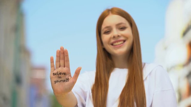 Young female showing palm with believe in yourself phrase, self-confidence