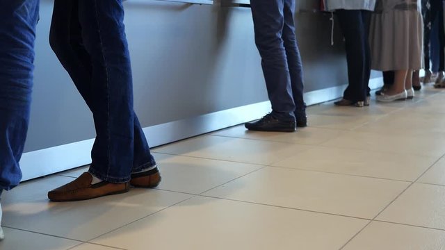 View of legs of customers standing n the modern office, getting served in the bank. Media. People are queuing for service in the department of a bank.