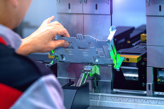 Workers bending sheet metal by CNC machines in industrial plants