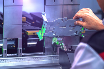 Workers bending sheet metal by CNC machines in industrial plants