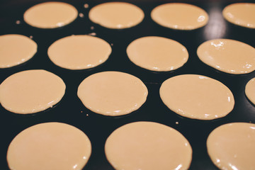 a stall vendor pouring creamy batter on a hot plate to make Dorayaki, a Japanese pancake-like dessert & a street snack popular