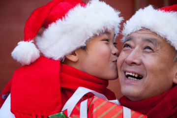 Grandfather and grandson holding gifts dressed in holiday attire