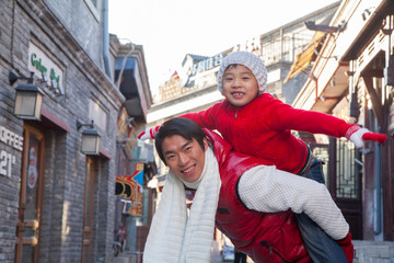Fototapeta premium Parent carrying child on shoulders dressed in holiday attire