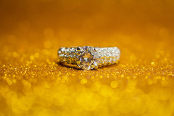 Jewelry wedding diamond ring on golden glitter bokeh light background