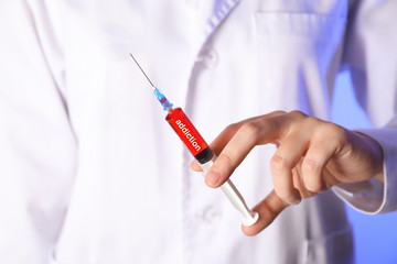 Doctor holding syringe full of addiction, closeup