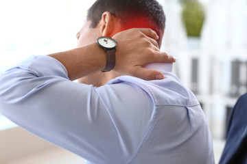 Young businessman suffering from neck pain in office