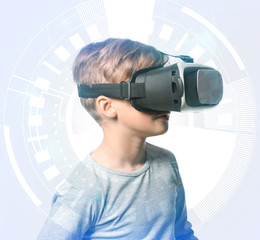 Cute boy wearing virtual reality glasses on light background