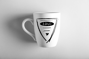 White cup with logo on light background