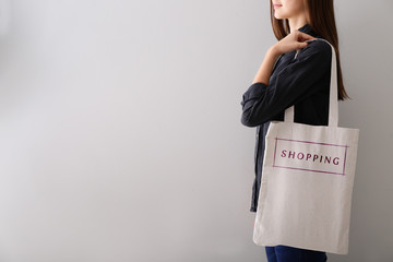 Woman with shopping bag on light background