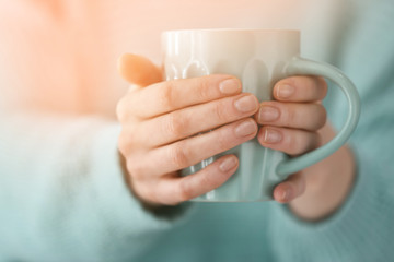 Young woman holding cup of coffee, closeup