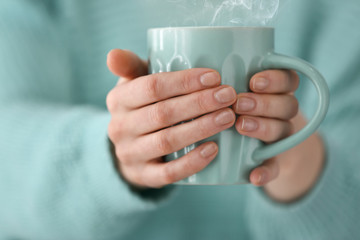 Young woman holding cup of coffee, closeup