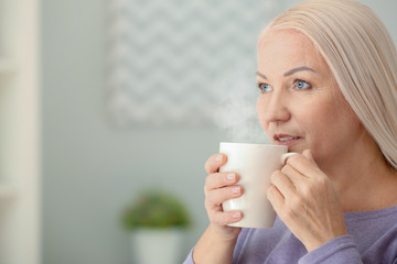Portrait of beautiful mature woman with cup of tea at home