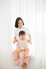 Young mother holding a baby standing in a tulle