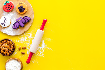 spooky halloween figures with rolling pin, flour, sugar, almond for cooking treat on yellow background top view mock up