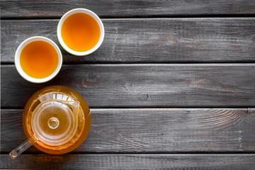 Tea brewing in pot and cups on wooden background top view space for text