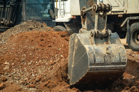 Close up yellow construction excavator working on the construction site. Bulldozer digging excavation earth for highway road build on a building site in summer. Earthwork construction building concept
