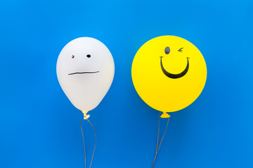 Treat depression concept. Balloons with frustrated and smiling faces on blue background top view