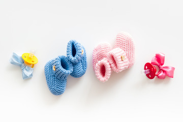 Booties for newborn boy and girl with dummy on white background top view