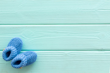 Blue knitted footwear for kids on mint green wooden background top view space for text