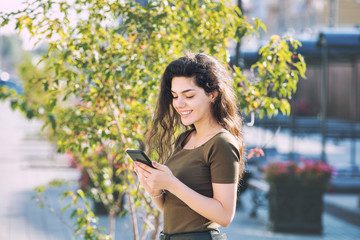 Young adult beautiful brunette girl in casual clothes with mobile phone happy on city street