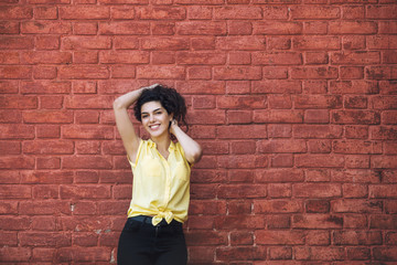 Young adult beautiful brunette girl in casual clothes on the background of a building with red brick walls