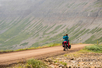 Woman backpacker with bike a shooting beautiful view of Westfjords in Iceland