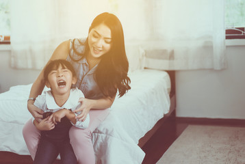 Asian single mom ticklish and carrying her cheerful daughter at home,Happy and funny - obrazy, fototapety, plakaty