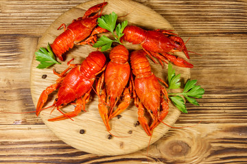 Boiled crayfish on cutting board on wooden table. Top view