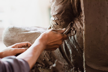 Selective focus sculptor hand molding clay.Professional artist worker creating a statue sculpture with wet clay.
