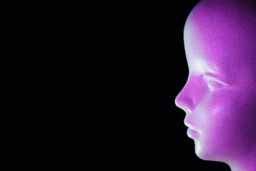 紫色の光で照らした発泡スチロール製の人形の横顔と黒いコピースペース