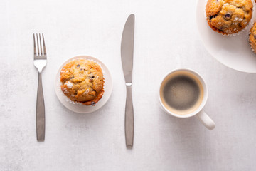 Blueberry muffins with white table place setting.