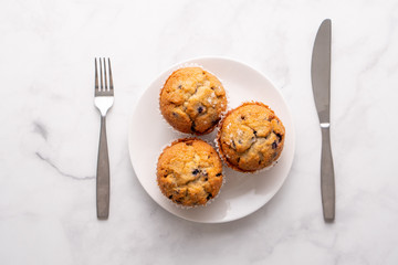 Blueberry muffins with white table place setting.