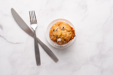Blueberry muffins with white table place setting.