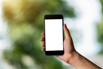 Mockup image of hand holding white mobile phone with blank screen with green nature background.