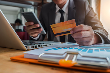 Male hold credit cards, conduct financial transactions via smartphone and data documents, put on...