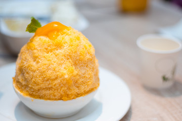Closeup thai milk tea Bingsu on white plate , Bingsu or Bingsoo is Korean shaved ice dessert with sweet toppings and fruit popular dessert.
