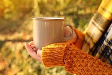 Autumn coffee. Autumn tea.  mug of hot drink in female  hands on a bright orange blurred vegetable...
