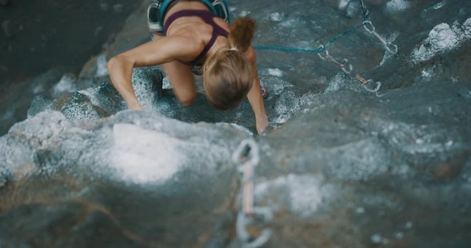 Top down angle of young fit woman lead rock climbing quickly up an outdoor sport route, amazing outdoors experiences