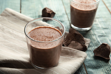 Glass with tasty chocolate milk on wooden table. Dairy drink