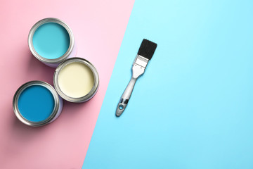 Open paint cans, brush and space for text on color background, top view