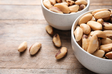 Bowls with tasty Brazil nuts on wooden table. Space for text