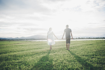 Pregnant wife with her husband enjoy walking outdoor with sunset in morning