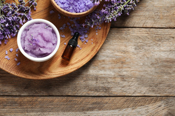 Plate with natural cosmetic products and lavender flowers on wooden table, top view. Space for text