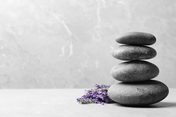 Spa stones and lavender flowers on grey table, space for text