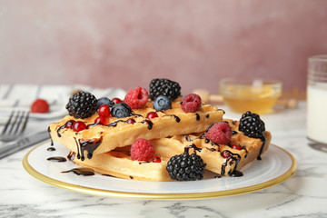 Delicious waffles with fresh berries served on white marble table against pink background