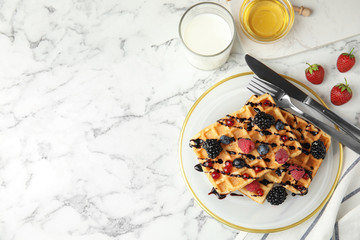 Delicious waffles with fresh berries served on white marble table, flat lay. Space for text